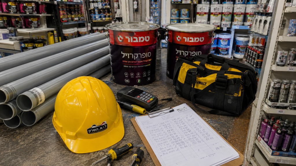 ציוד לשיפוצניק — קסדה, תיק DeWalt, מברגים, דלי טמבור ורשימת חומרים בדלפק החנות ציוד לשיפוצניק — קסדה, תיק DeWalt, מברגים, דלי טמבור ורשימת חומרים בדלפק החנות